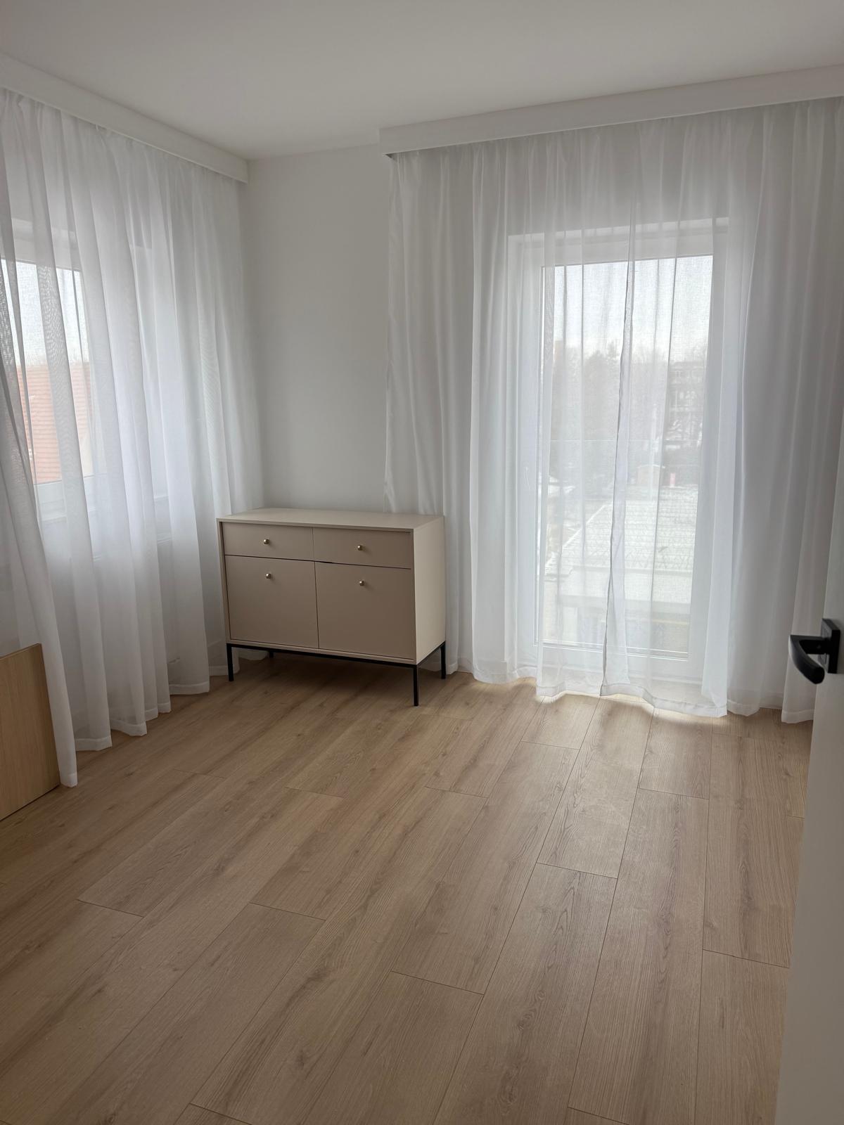 Jasna komoda na smukłej, czarnej podstawie.