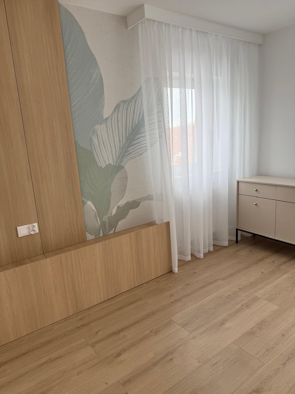 Roślinny motyw ścienny zestawiony z zabudową w odcieniu drewna.