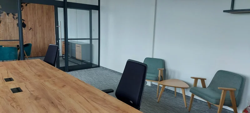 A work table and an intimate conversation corner with armchairs in subdued green.