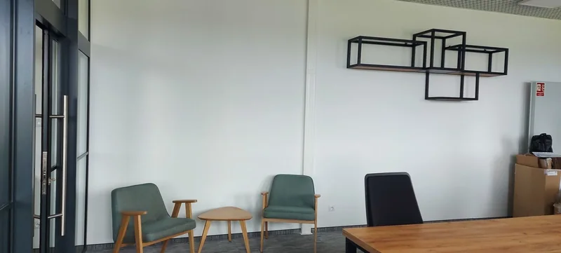 Conversation corner with two armchairs, a table and geometric wall shelves.