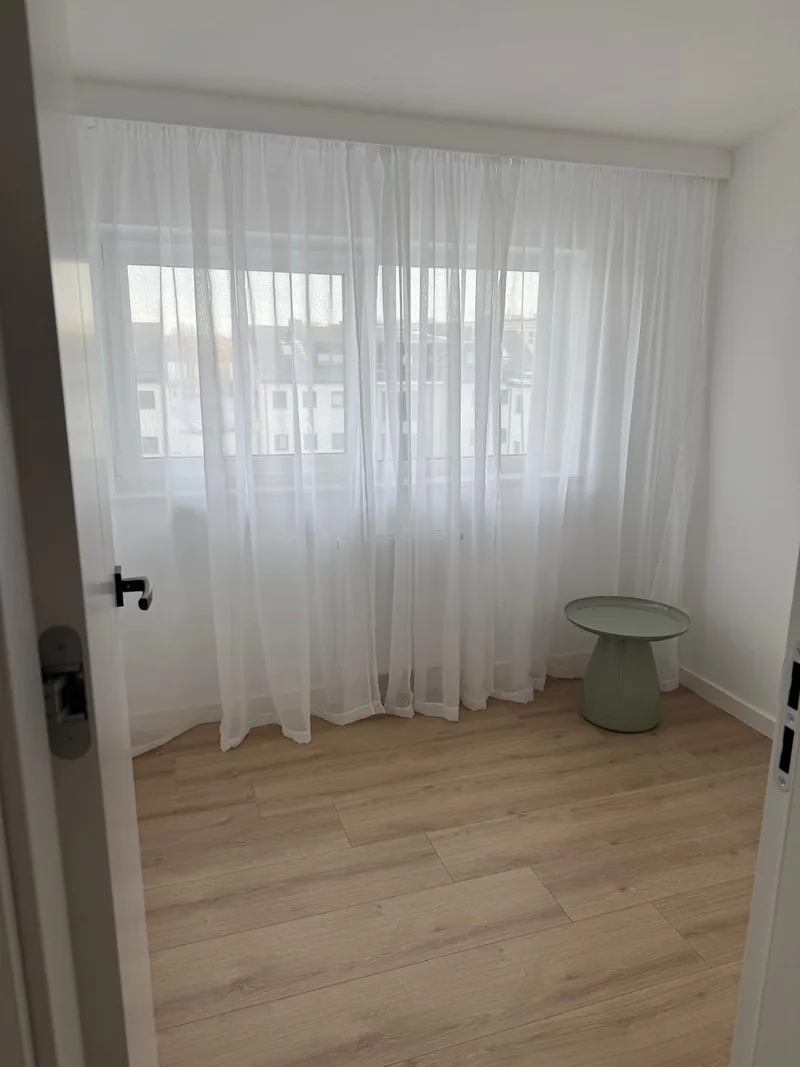 Light curtains and a green table in a bright room.