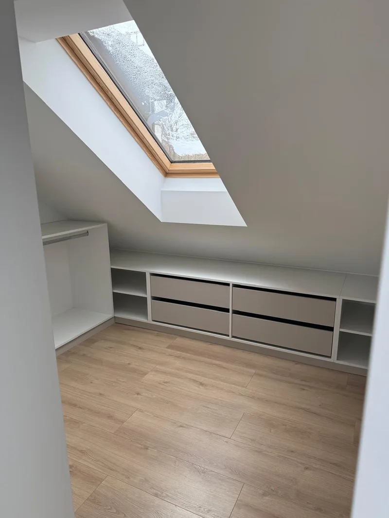 Low cabinetry with drawers and shelves fitted beneath the sloping ceiling.