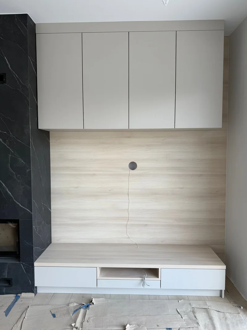 TV unit with light wood finish, lower drawers and upper cabinets.