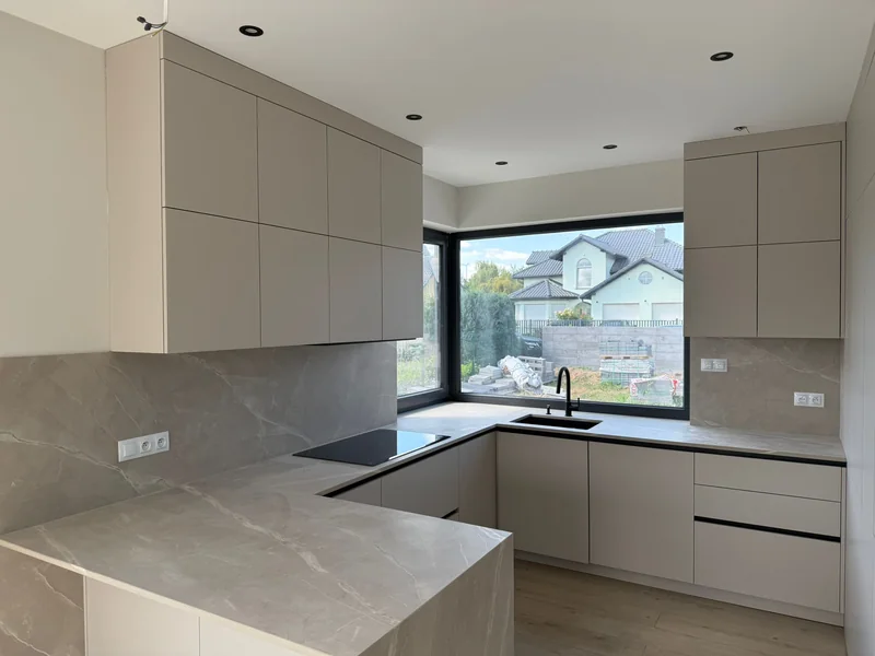 Bright kitchen with a peninsula, corner window and subtle stone pattern.