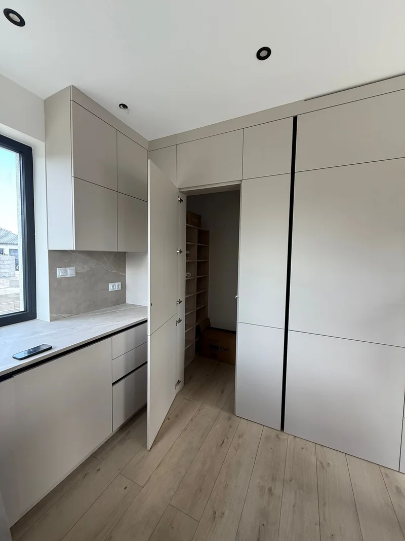 The passage to the pantry is hidden in the plane of the kitchen fronts.
