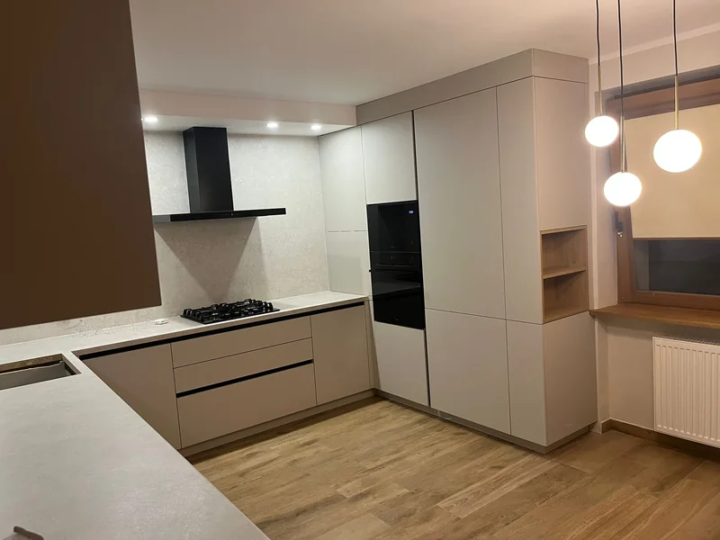 Tall cabinetry with black appliances and an open recess in the shade of wood.