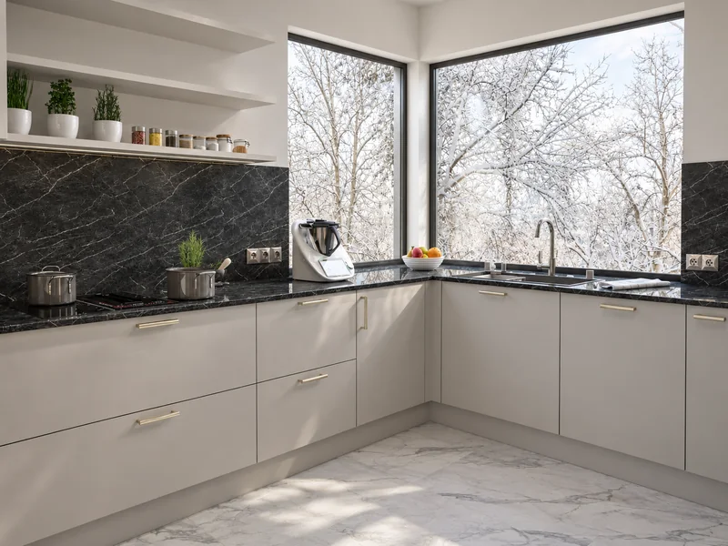 A bright kitchen with a dark, veined countertop and gold-tone handles.